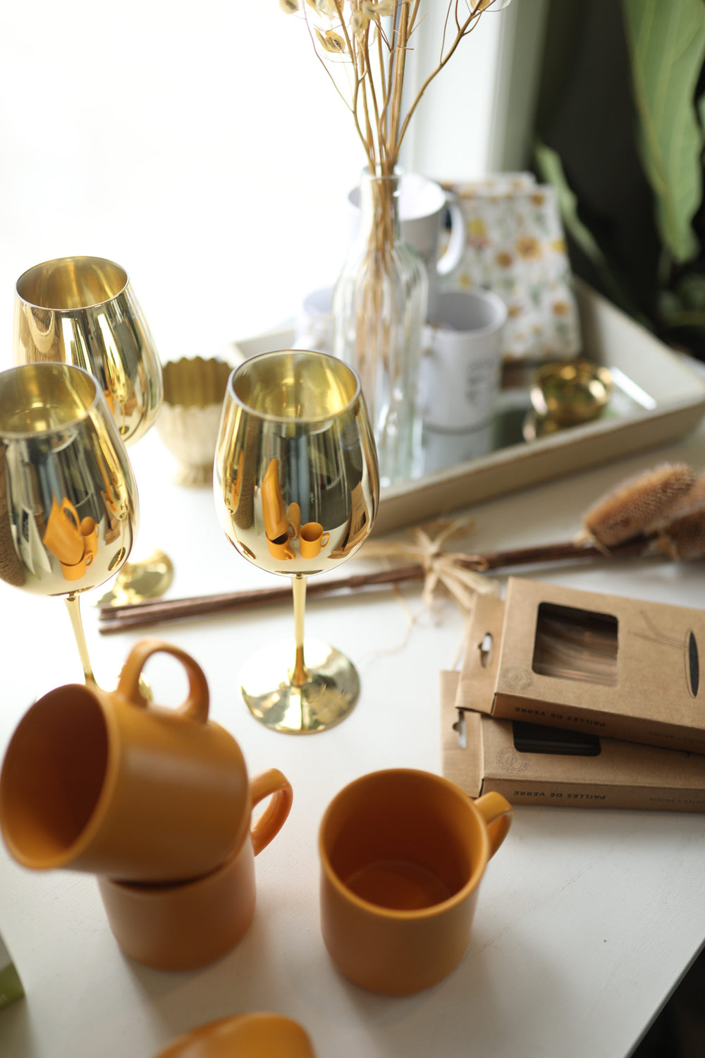 gold wine glasses, amber yellow mugs, glass straws with dried flowers