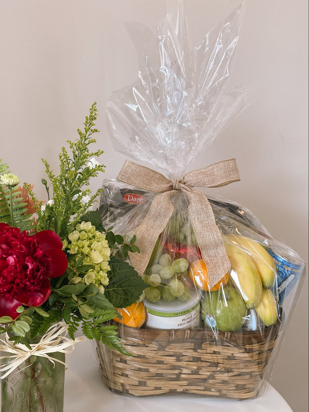 Bouquet of flowers and a fruit basket on a white surface with a neutral background