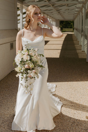 Bride in a white wedding dress holding a bouquet on a stone path.