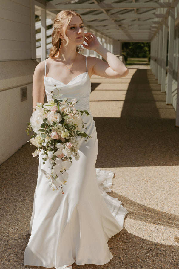 Bride in a white wedding dress holding a bouquet on a stone path.